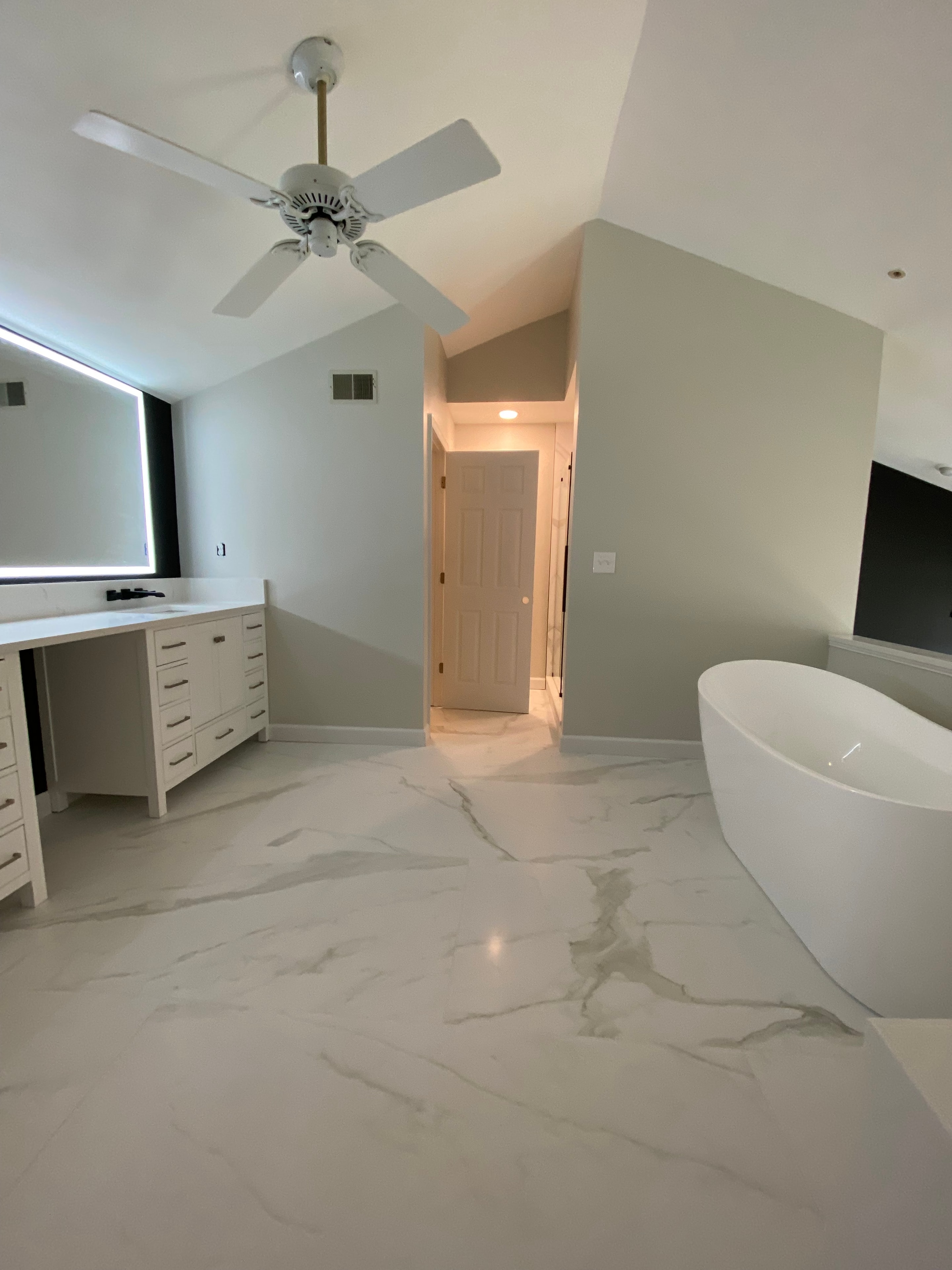 Modern bathroom vanity with double sinks, large mirrors, and wall-mounted lights in a white interior